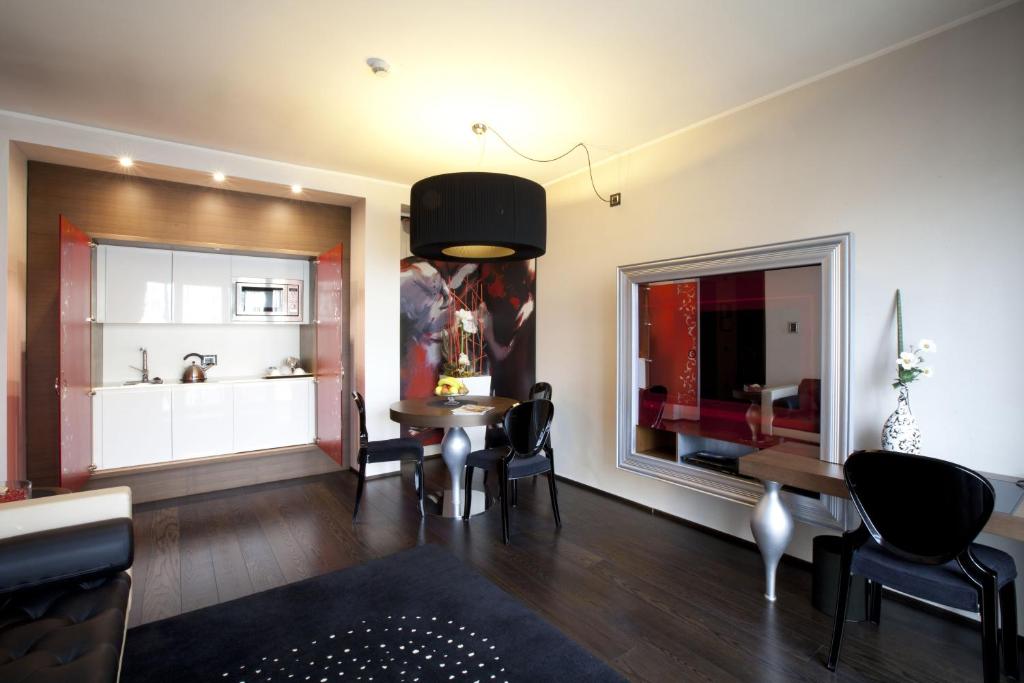 ein Wohnzimmer mit einem Tisch und Stühlen sowie eine Küche in der Unterkunft Palace Hotel Moderno in Pordenone