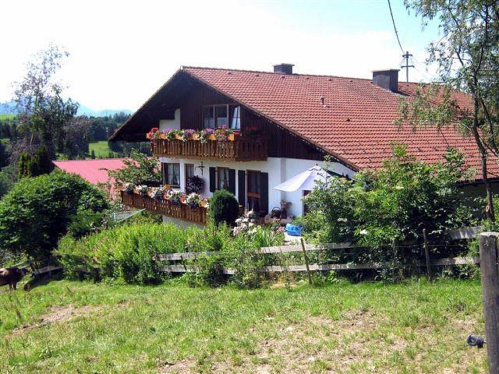 une maison avec un toit rouge et des fleurs sur le balcon dans l'établissement Haus Bergblick, à Oy-Mittelberg