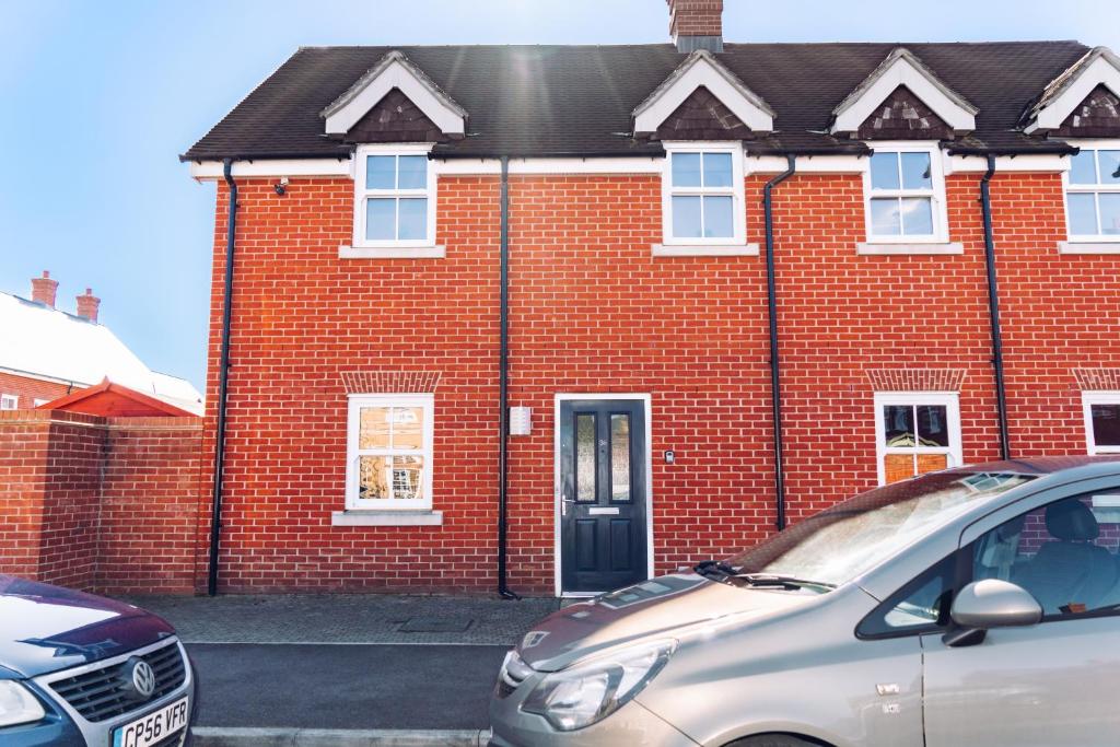 a red brick house with a car parked in front of it at Detached Coach House in Colchester