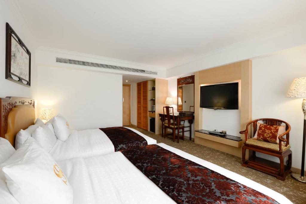 a hotel room with a white bed and a television at Hotel Sunshine in Kaohsiung