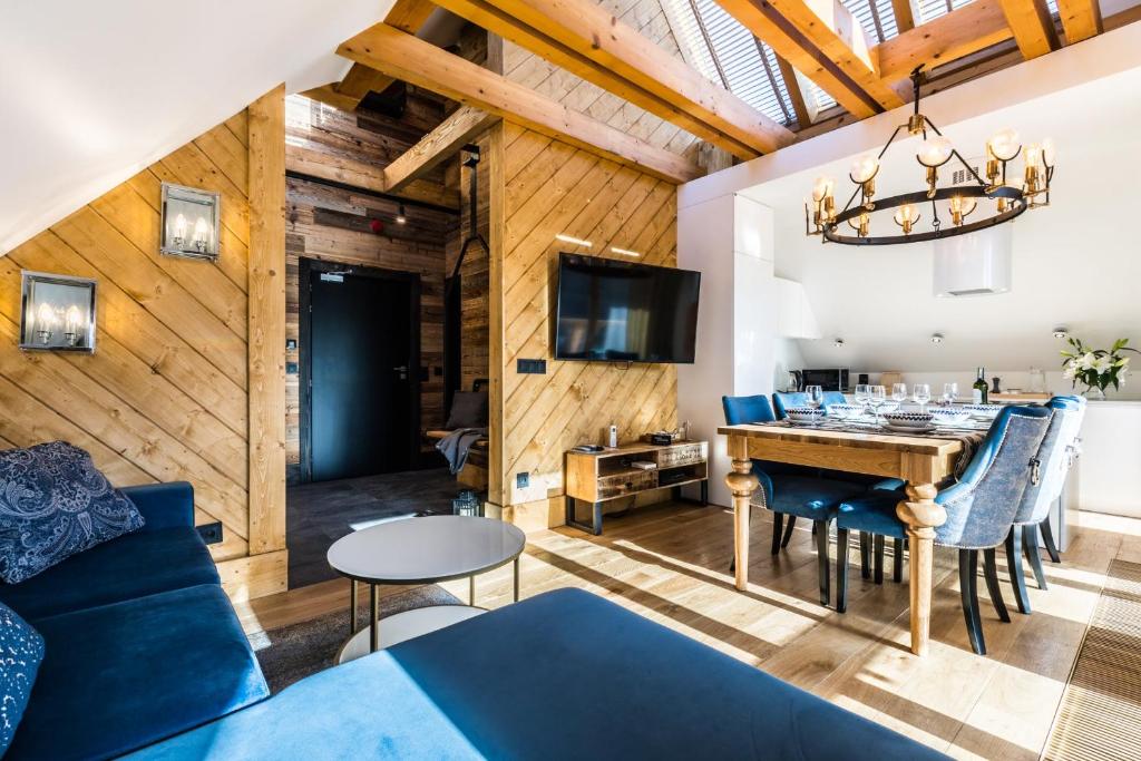 a dining room and living room with a blue couch and a table at Luxury Apartments in Zakopane
