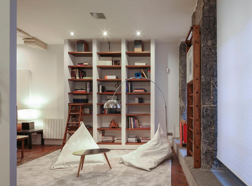 een woonkamer met een tafel en een boekenplank bij Casco Viejo Comodidad y elegancia by Urban Hosts in Bilbao