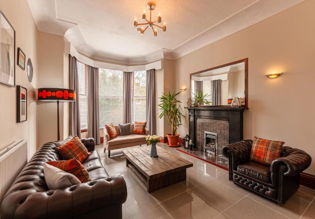 a living room with a leather couch and a fireplace at Nelson Manor in Dundee