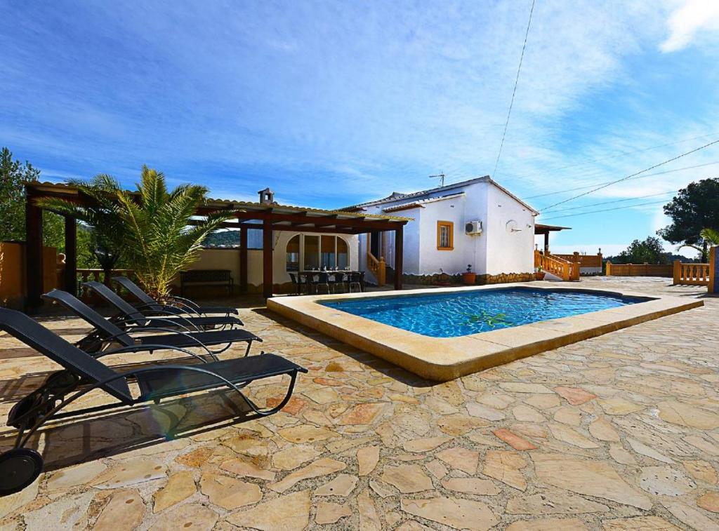 a swimming pool with lounge chairs and a house at Villa Iris - Plusholidays in Calpe