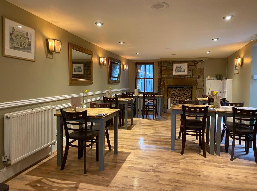 um restaurante com mesas e cadeiras e uma lareira em The Covenanter Hotel em Falkland