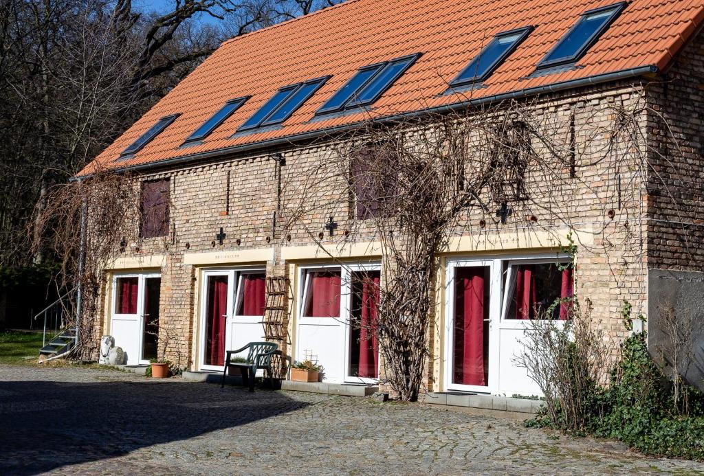 ein Backsteingebäude mit rotem Dach und weißen Türen in der Unterkunft Landhof Potsdam in Potsdam