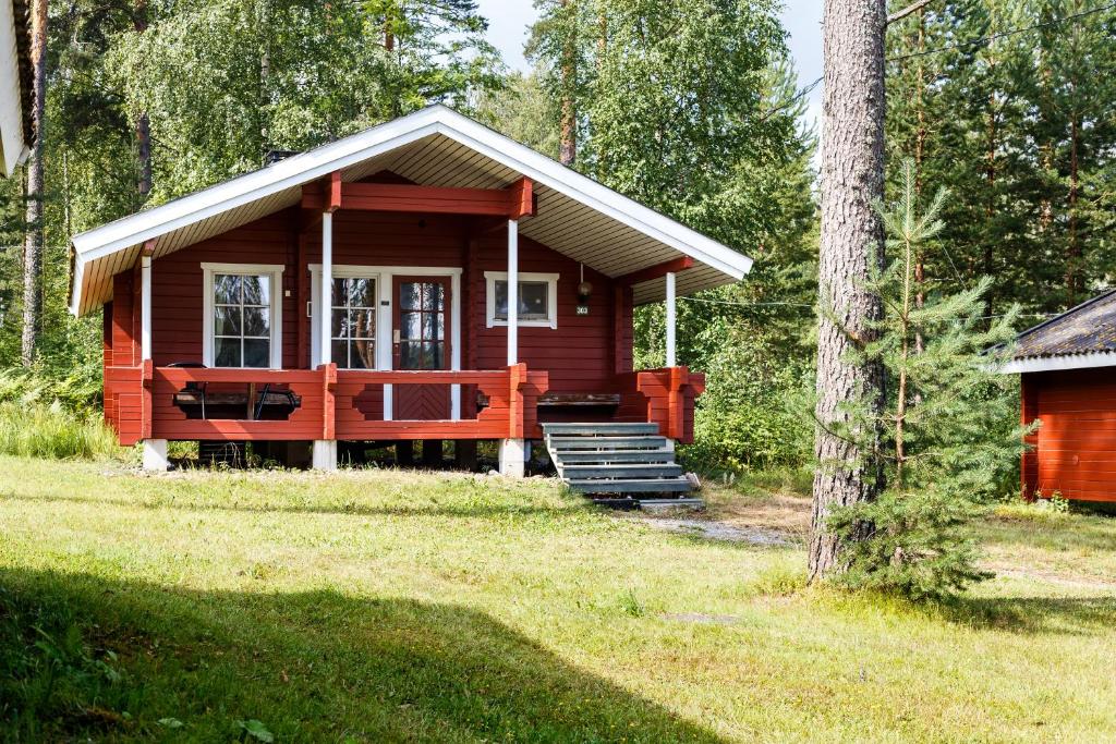 a small red cabin with a porch in the woods at Punkaharju Resort in Punkaharju