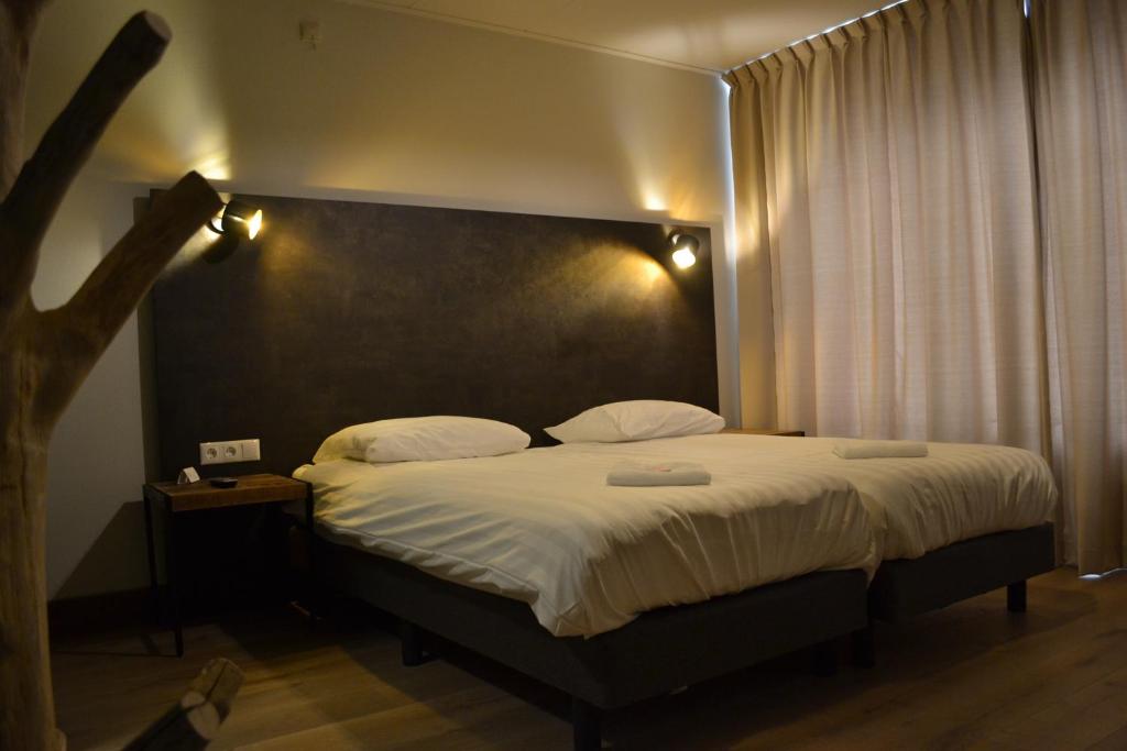 1 dormitorio con 1 cama grande con sábanas blancas en Hotel & Eetk'fee de VLiK en Ospel