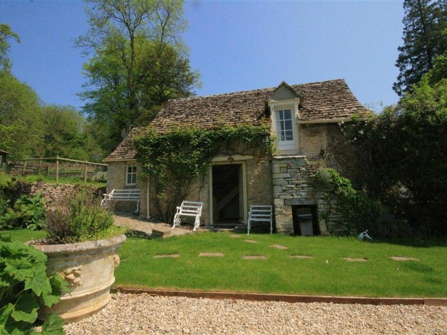 an old stone house with a porch and a yard at Mayfly Cottage in Quenington
