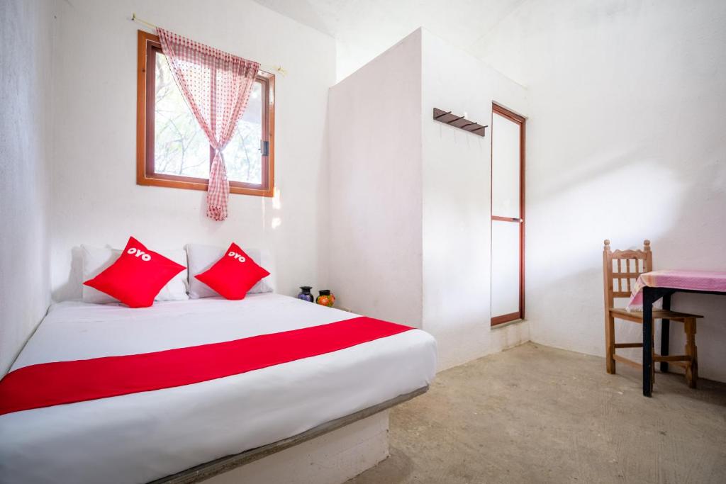 Cette chambre comprend un lit avec des oreillers rouges et un bureau. dans l'établissement OYO Cabañas Abril, Mazunte, à Mazunte