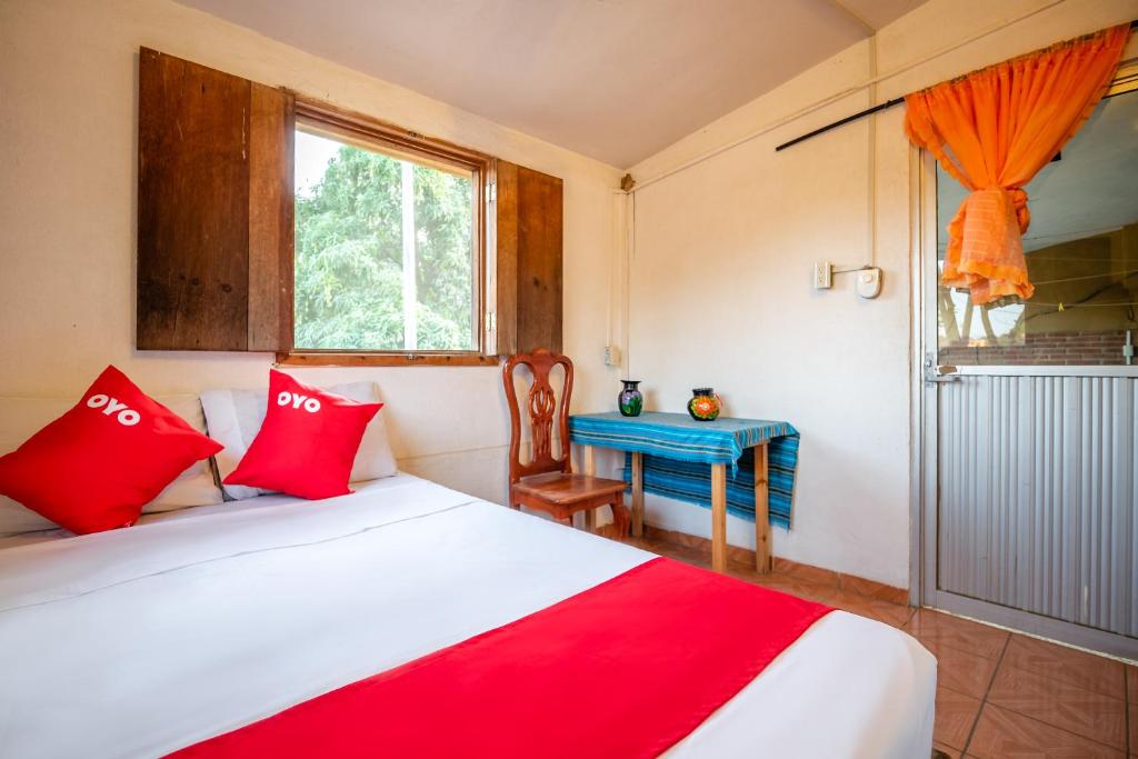a bedroom with a bed with red pillows and a table at OYO Cabañas Abril, Mazunte in Mazunte
