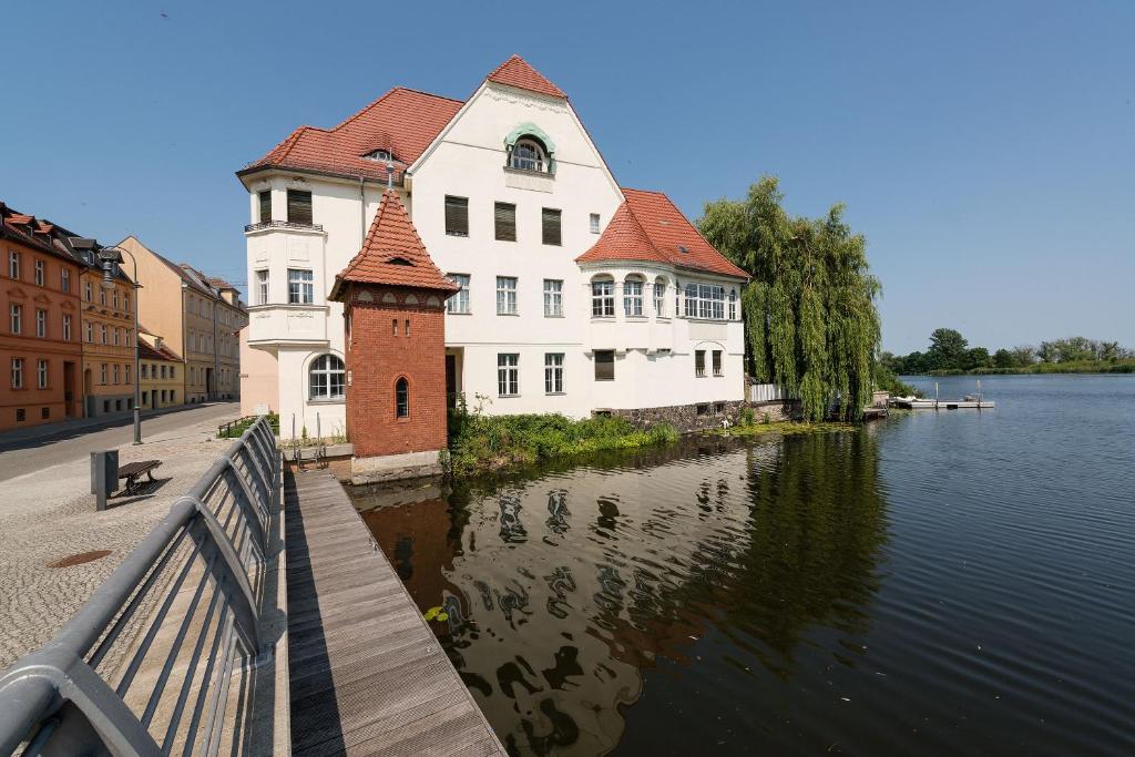 ein großes weißes Gebäude neben einem Wasserkörper in der Unterkunft Fewo auf der Dominsel-LOTUS in Brandenburg an der Havel