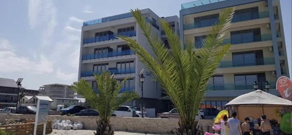 a building with a palm tree in front of a building at VELVET RESIDENCE in Mamaia Sat/Năvodari