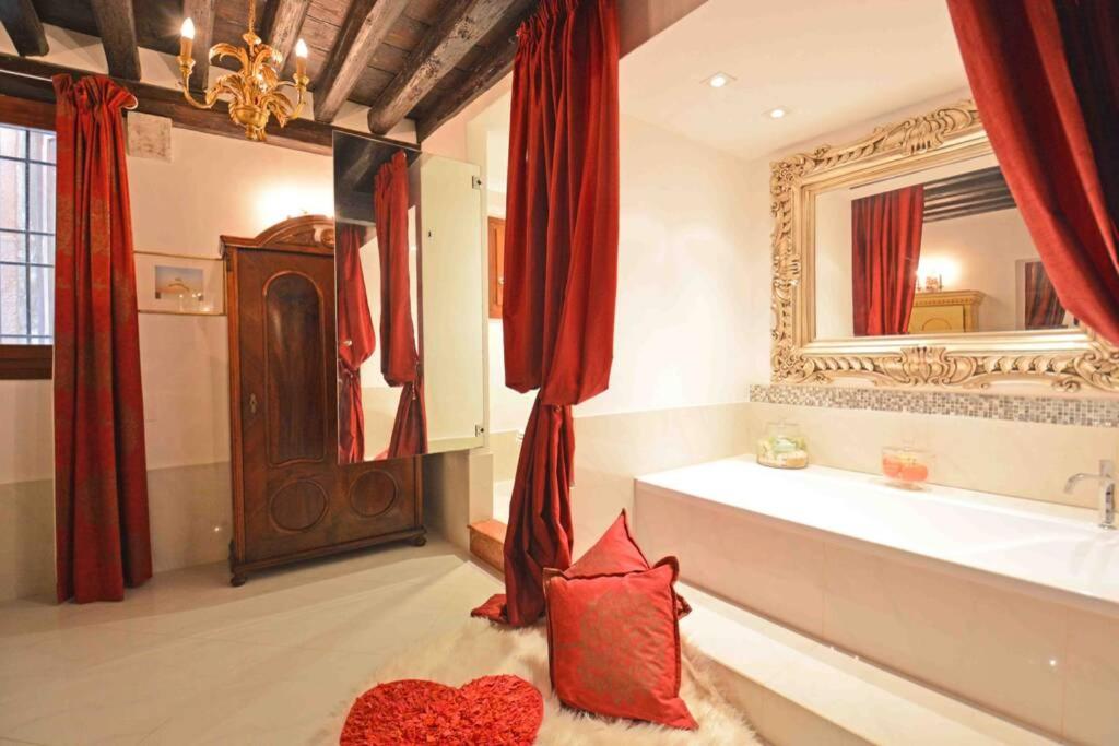 a bathroom with a tub and a mirror and red curtains at Zattere Cottage close to Guggenheim in Venice