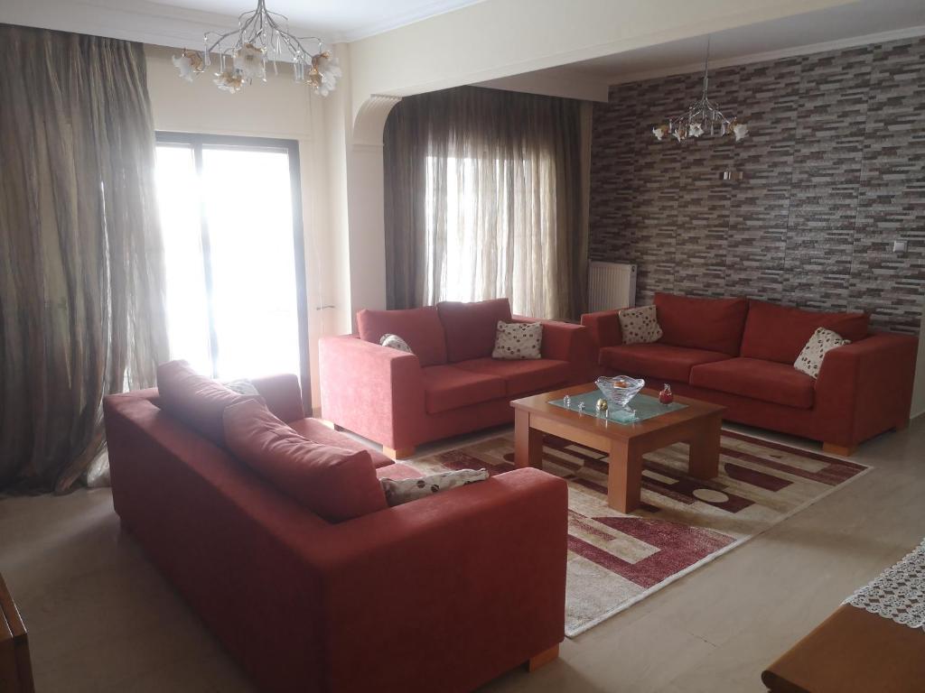 uma sala de estar com dois sofás vermelhos e uma mesa em Comfortable Apartment in Kato Toumpa em Tessalônica