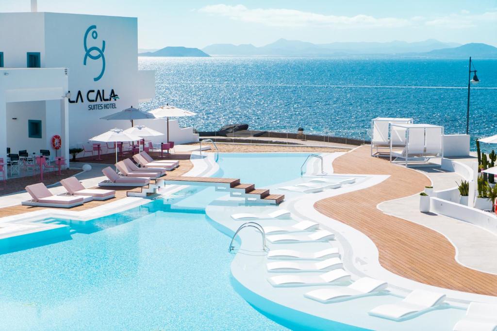 una piscina con sillas y el océano en CalaLanzarote Suites Hotel - Adults Only, en Playa Blanca