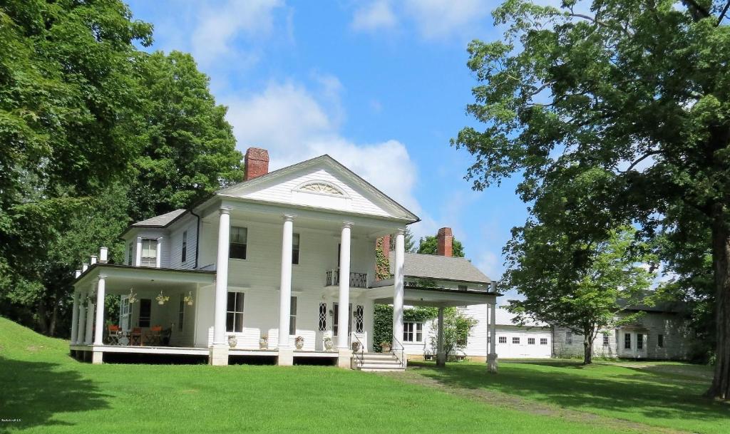 une maison blanche avec une terrasse couverte et une pelouse dans l'établissement Granville House, à Great Barrington