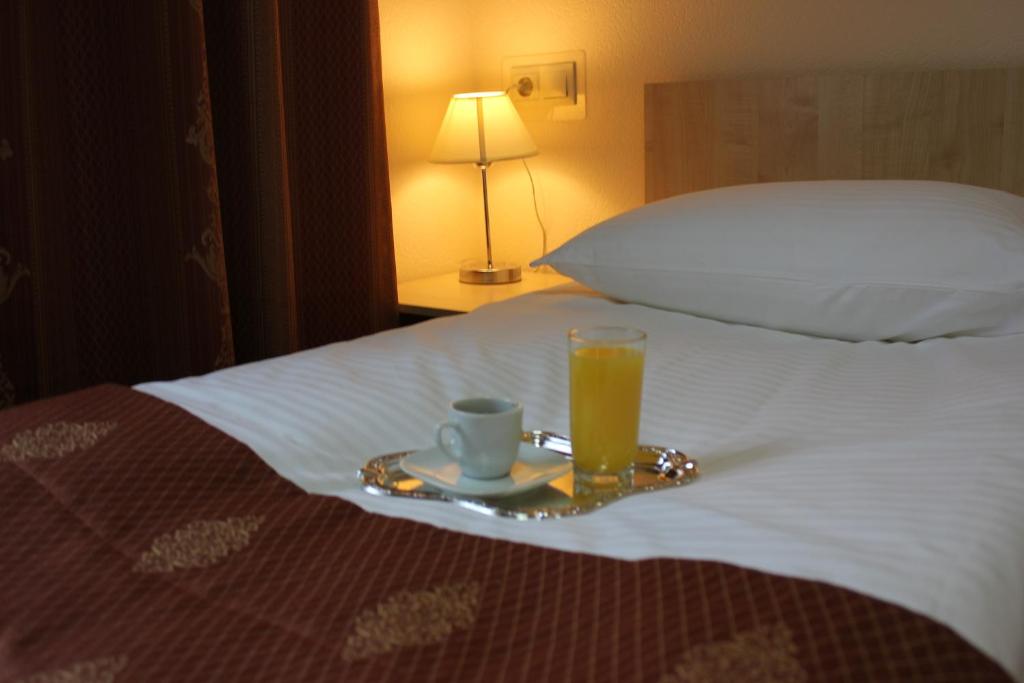 a tray with a cup and a glass of orange juice on a bed at Mini Hotel Konstantinych in Kislovodsk