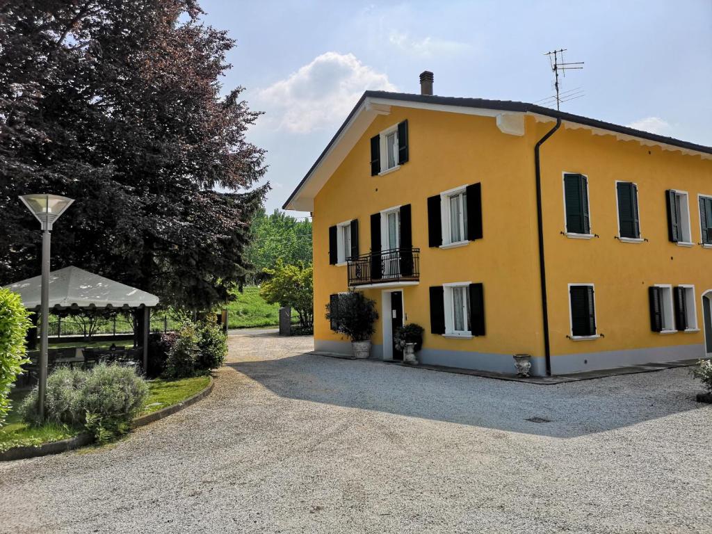 a large yellow house on a gravel driveway at La Meridiana Affittacamere in Colorno