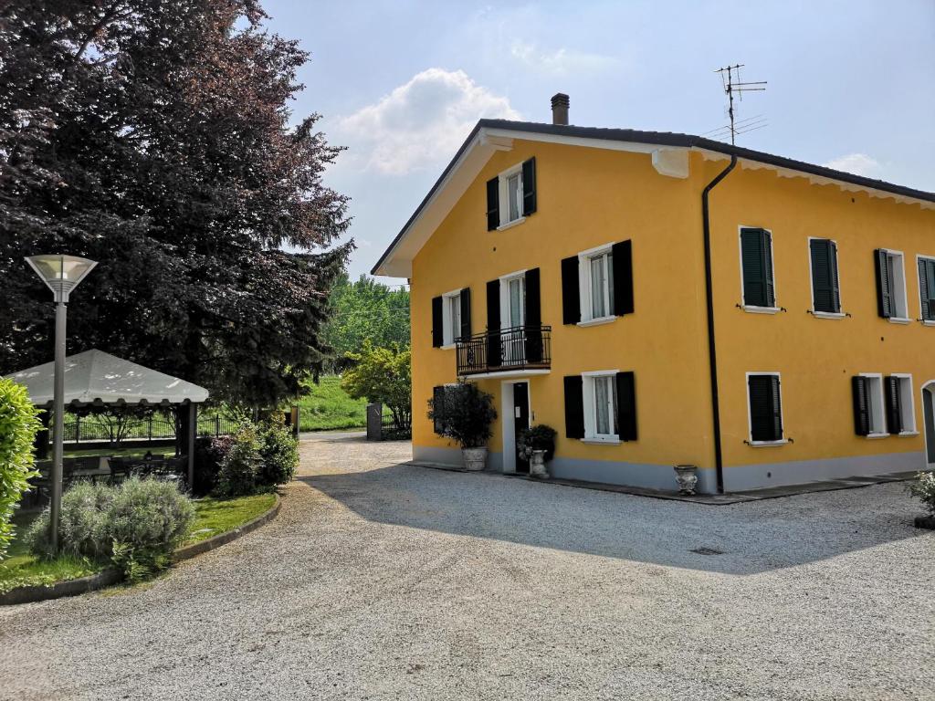 una gran casa amarilla en una entrada de grava en La Meridiana Affittacamere, en Colorno