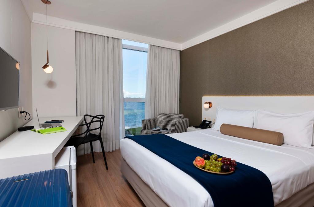 a hotel room with a bed with a bowl of fruit on it at Píer Vitória Hotel in Vitória