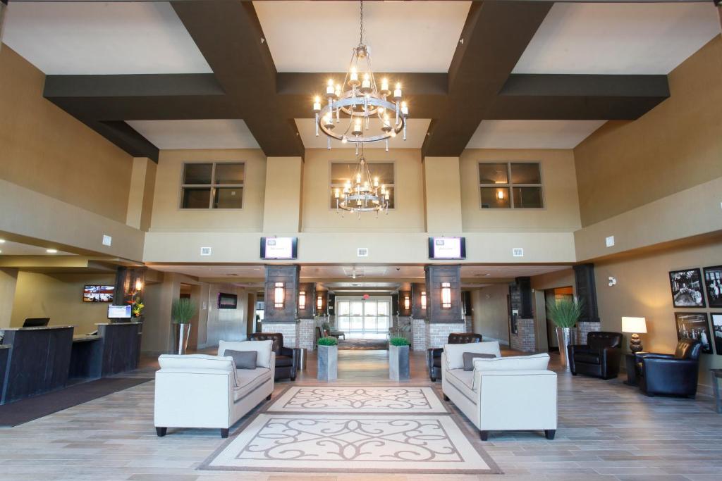 een lobby van een hotel met witte stoelen en een kroonluchter bij Pomeroy Inn & Suites at Olds College in Olds