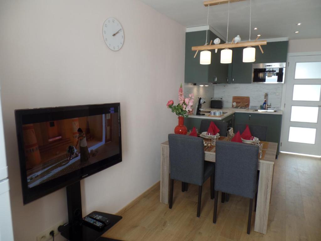 uma sala de estar com televisão e uma mesa com cadeiras em Beaulieu em Blankenberge