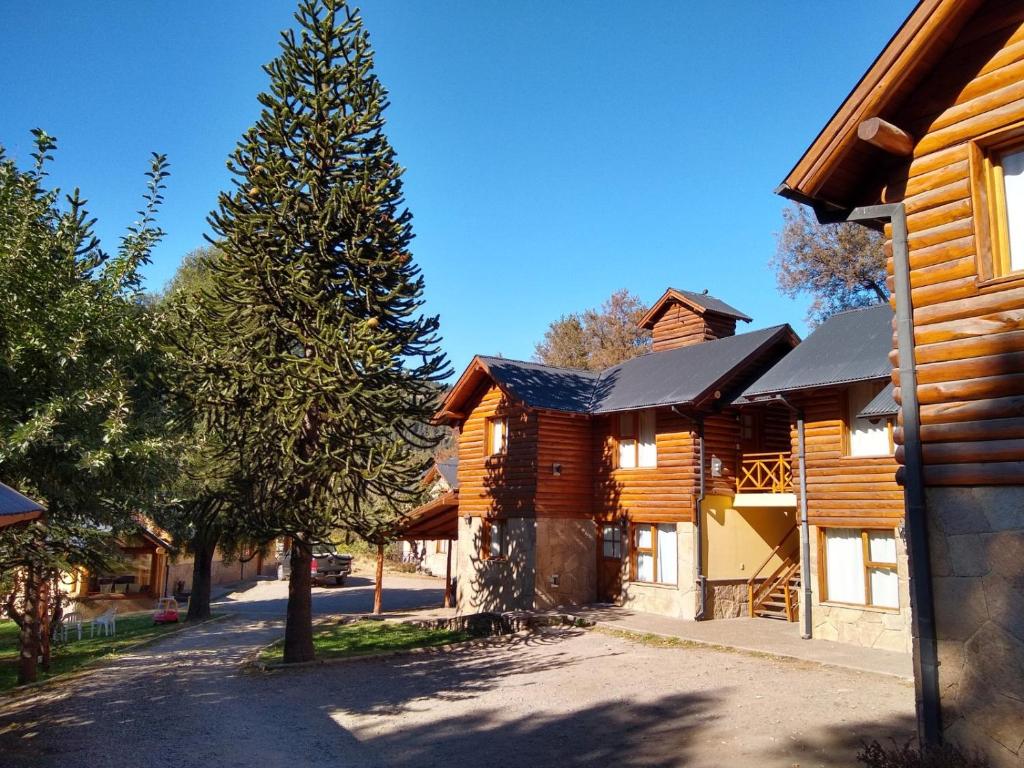 a log cabin with a tree in front of a street at Apart Peumayen in San Martín de los Andes