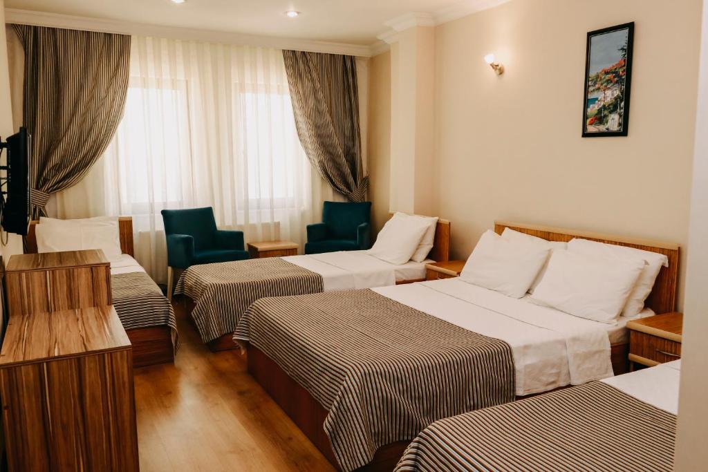 a hotel room with three beds and chairs at Ece Hotel Eceabat in Eceabat