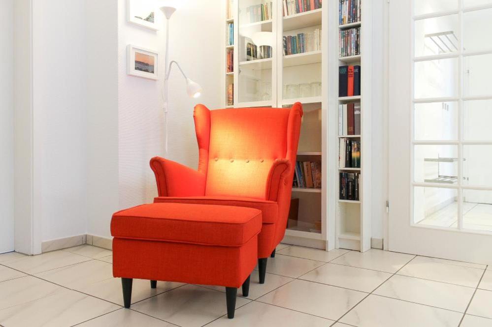 - un fauteuil rouge et un pouf rouge dans la chambre dans l'établissement Ferienwohnung Wohldfühlen, à Timmendorfer Strand