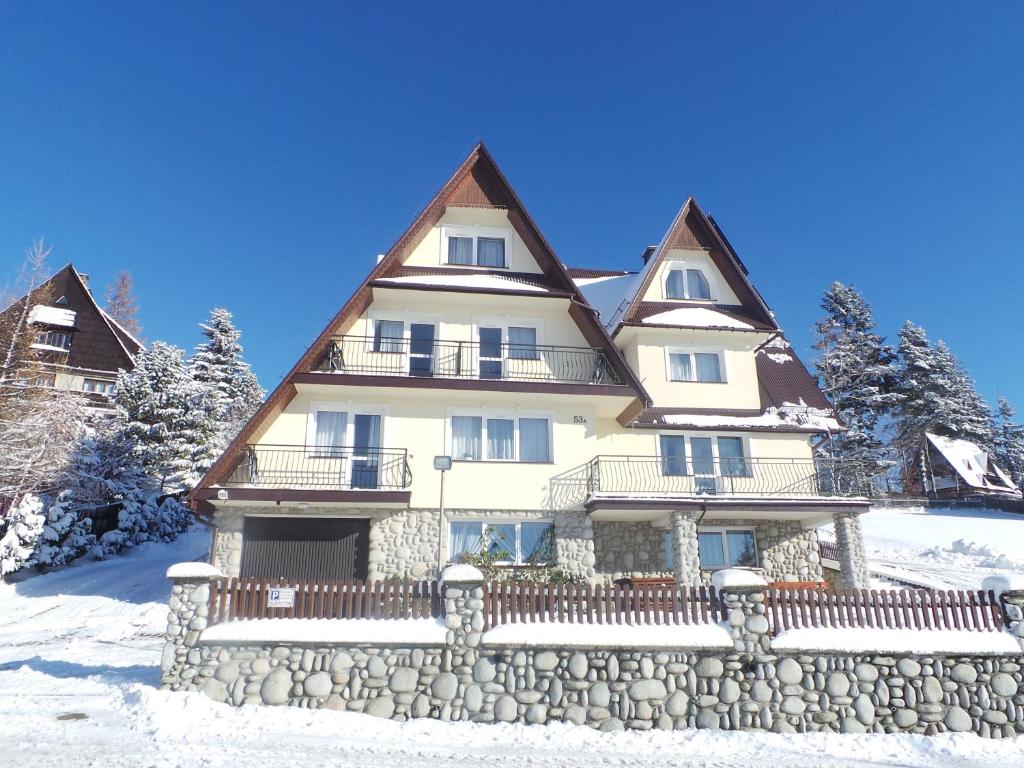 una casa grande con una valla de piedra en la nieve en 9 Sił Murowany Dom, en Bukowina Tatrzańska