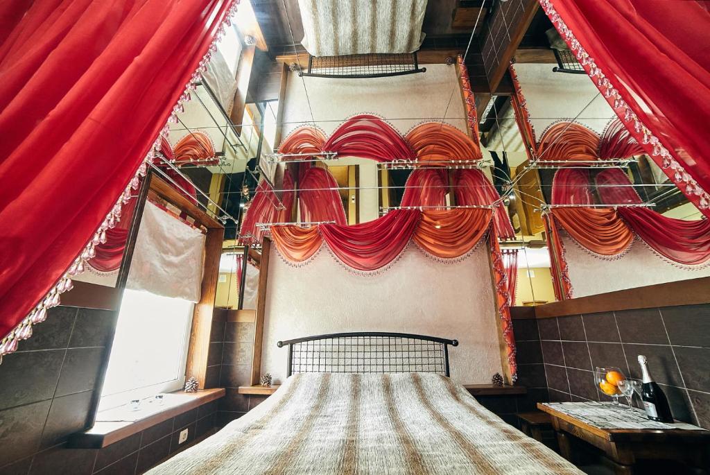 a room with red curtains and a bed in it at Mirrors in Vinnytsya