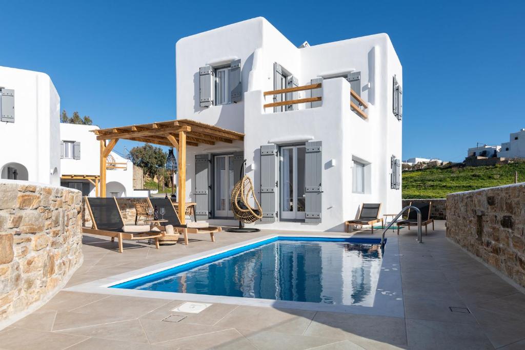 une villa blanche avec une piscine en face de celle-ci dans l'établissement NAXIAN SUNSET VILLAS, à Naxos Chora