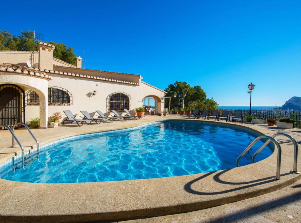 a swimming pool with chairs and a house at Villa Pinosoro20 - Plusholidays in Calpe