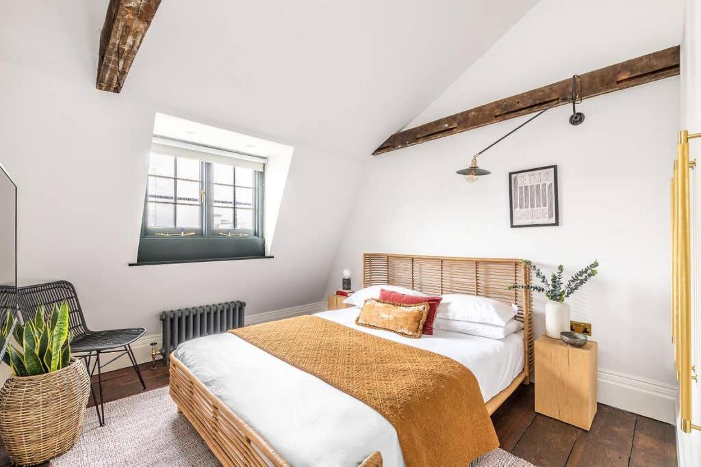 een slaapkamer met een bed en een stoel bij Cosy Loft Apartment - minutes from Angel Tube St. in Londen