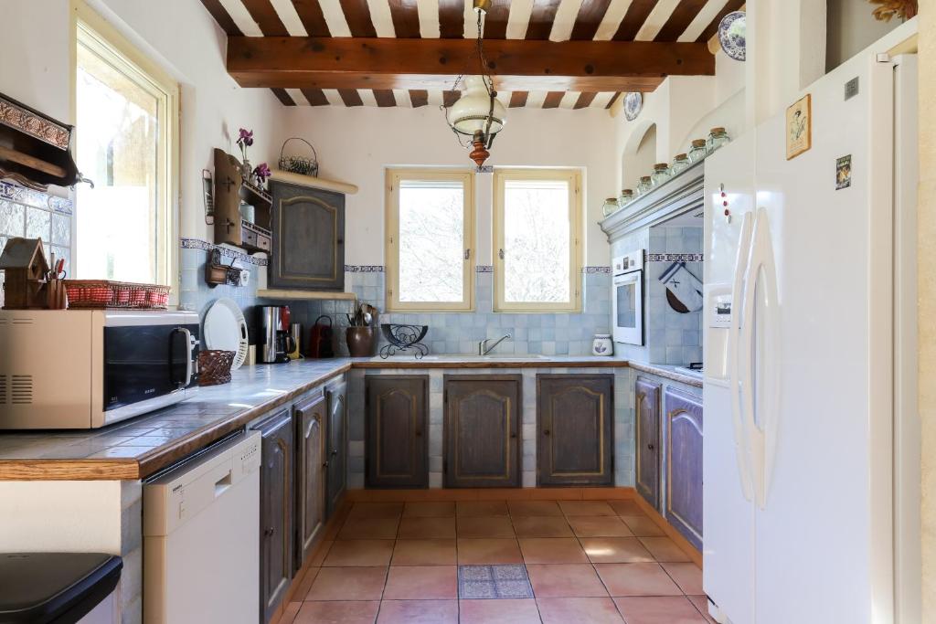 a kitchen with wooden cabinets and a white refrigerator at Le Mas du Lac in Saint-Rémy-de-Provence