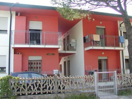 a red building with a car parked in front of it at Villa Milviana appartamento in Rosolina Mare