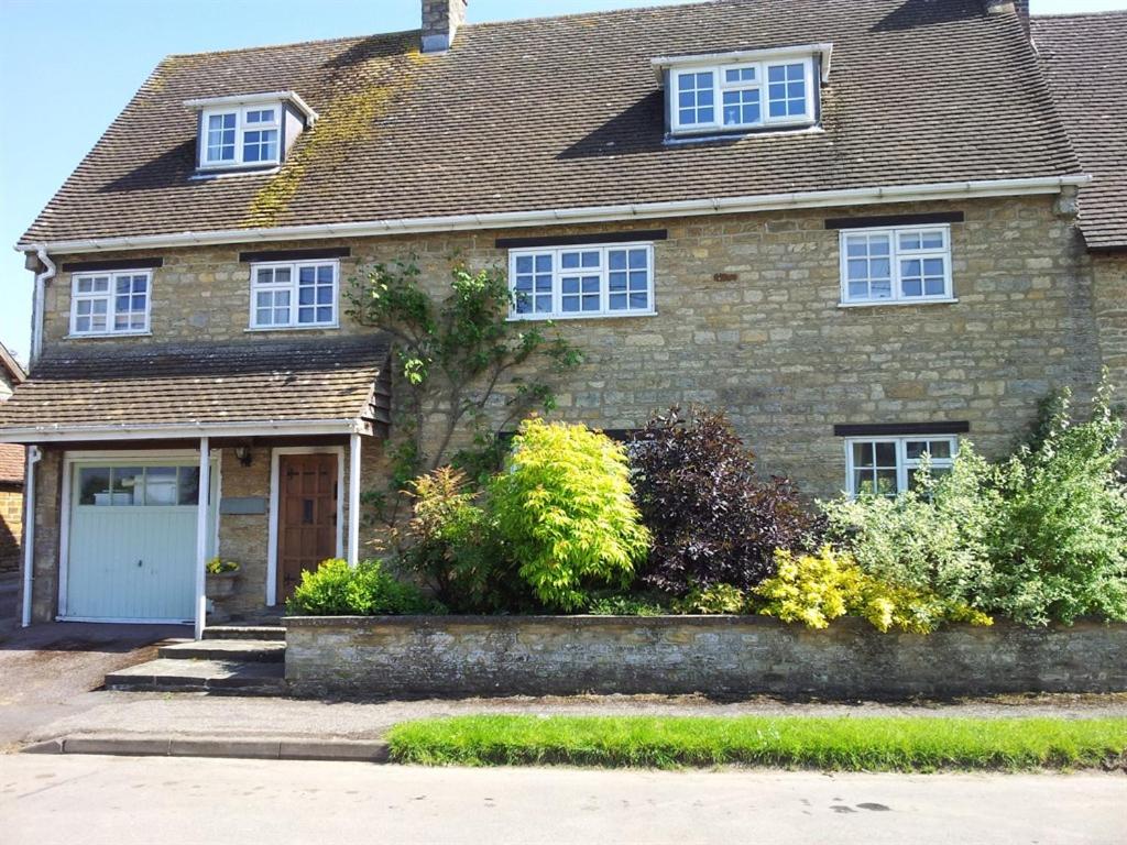 uma casa de tijolos com uma porta branca e janelas em Stone House em Sulgrave