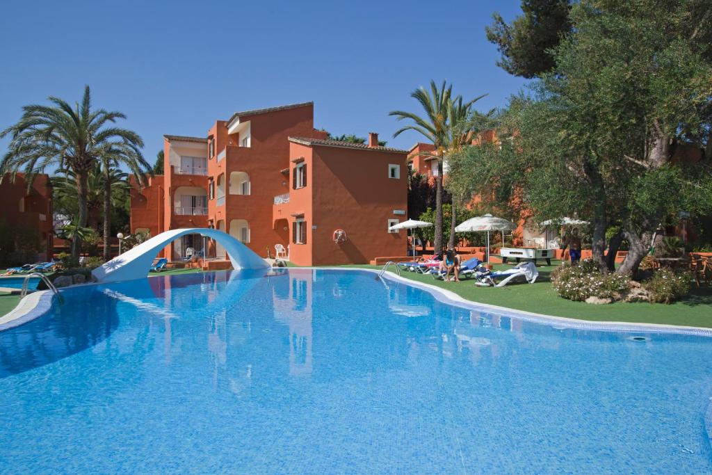 a large swimming pool with a bridge in a resort at HSM Club Torre Blanca in Sa Coma