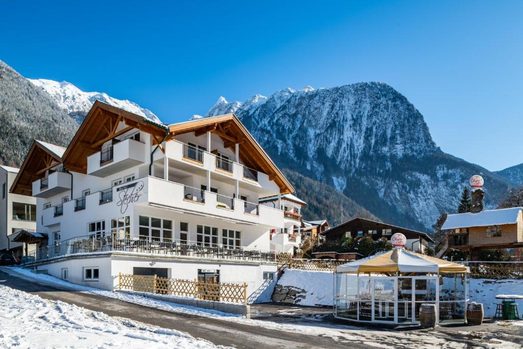 a hotel in the snow with mountains in the background at Hotel Stecher in Oetz