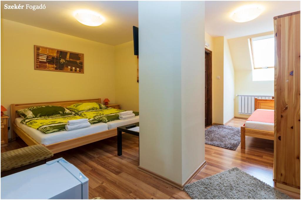 a bedroom with a bed with yellow walls and wooden floors at Szekér Fogadó in Bátonyterenye