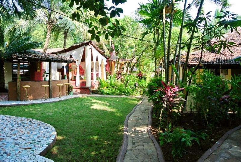 einen Garten mit einem Haus und einem Garten mit einer Rasenfläche sidx sidx sidx in der Unterkunft "Sunny Cow" Village Villa in Anjuna