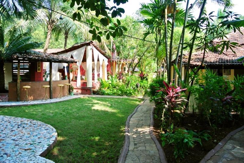 un jardín con una casa y un patio con césped sidx sidx sidx sidx en "Sunny Cow" Village Villa, en Anjuna