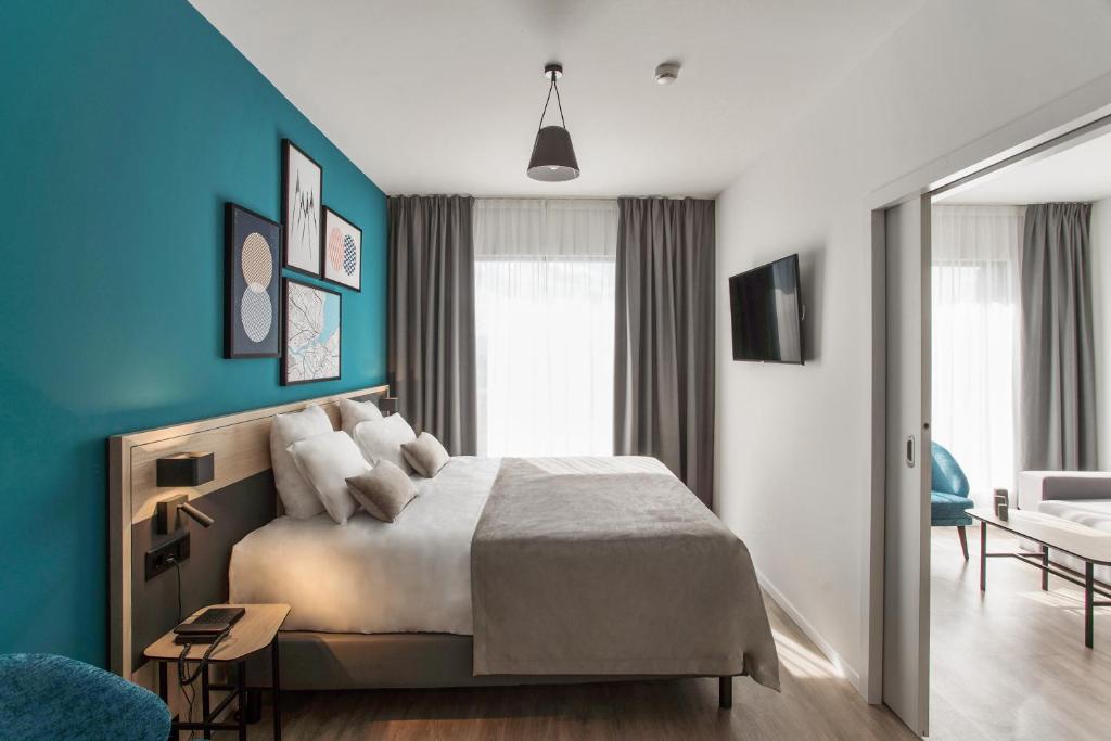 ein Schlafzimmer mit einem Bett und einer blauen Wand in der Unterkunft Appart'City Collection Genève Aéroport - Vernier in Genf