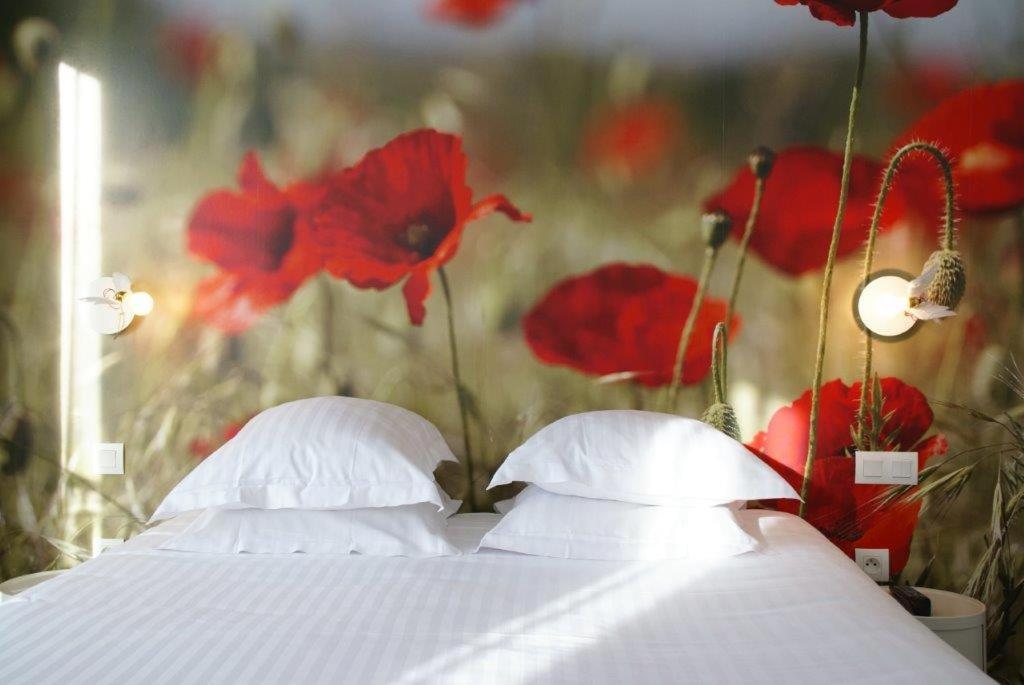 a bed with red poppies on the wall at L’Échappée Belle in LʼIsle-Jourdain