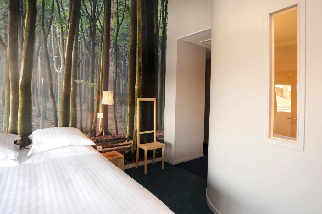 a bedroom with a mural of trees on the wall at L’Échappée Belle in LʼIsle-Jourdain