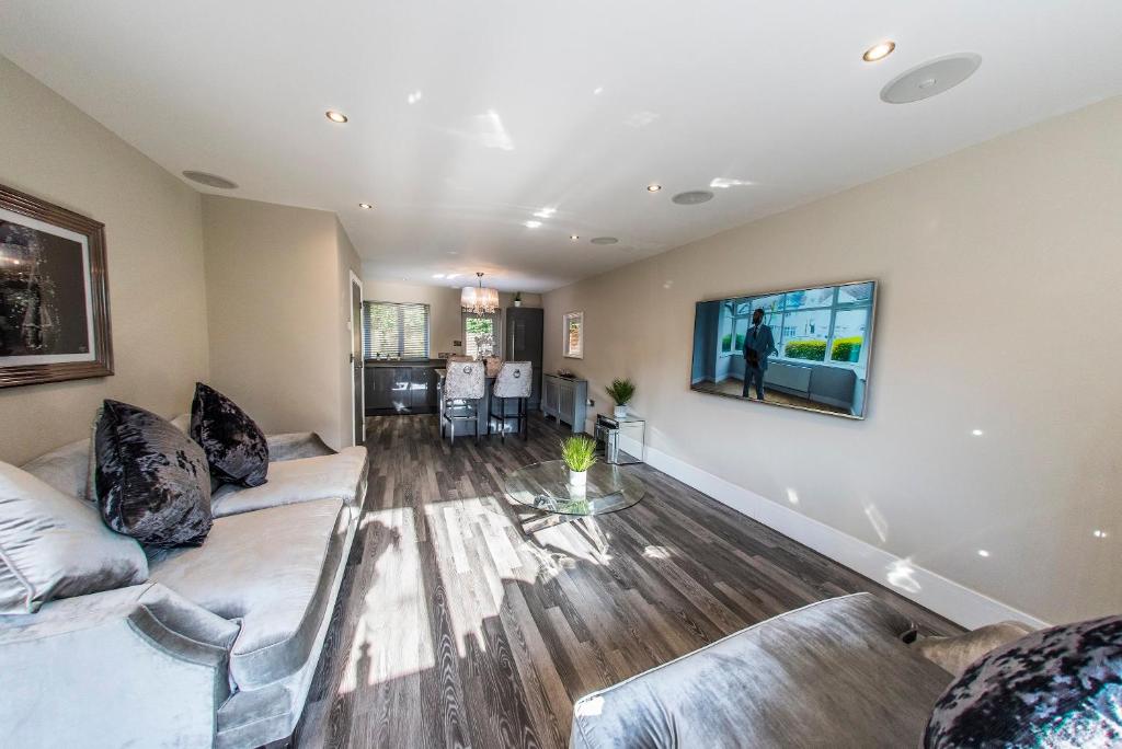 a living room with a couch and a tv on a wall at Courtyard Holiday Homes in Southport