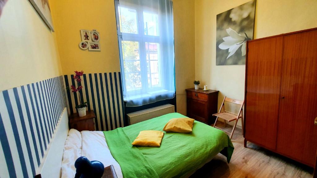 Un pequeño dormitorio con una cama verde y una ventana en The apartment in strict city center. Self check-in en Cracovia