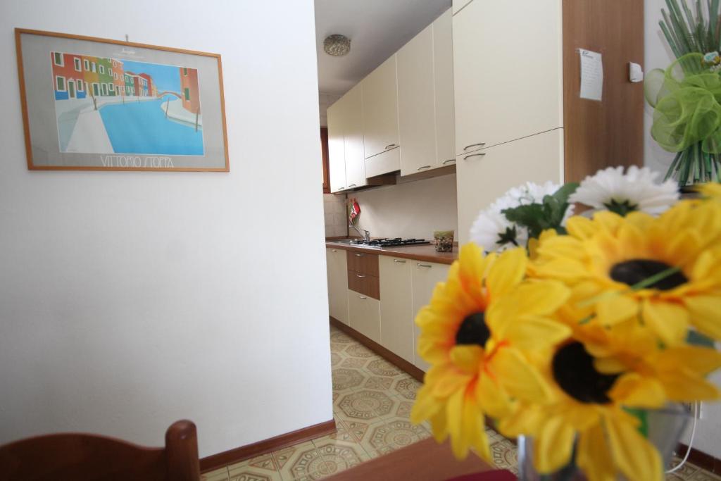 una cocina con un jarrón con flores amarillas. en Villa Tatiana appartamento en Rosolina Mare