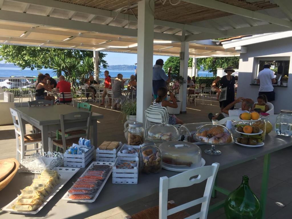 トレヴィニャーノ・ロマーノにあるSkipper White Guest Houseの海辺に座る人々と食べ物を乗せたテーブル